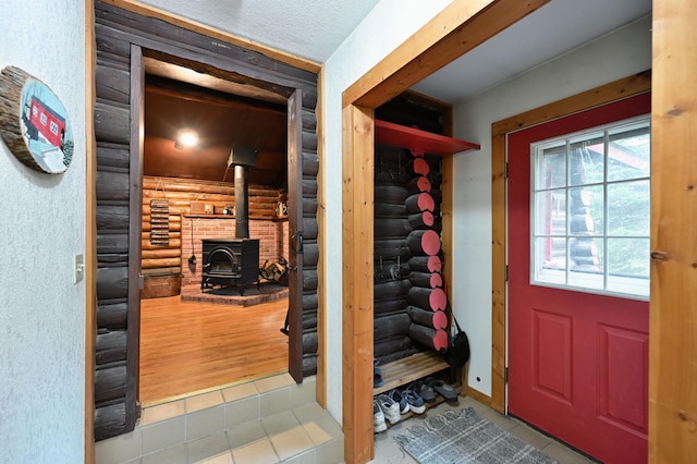 9262 Park Ave, Solon Springs, WI 54873 - entryway with log walls, tile patterned flooring, and a wood stove