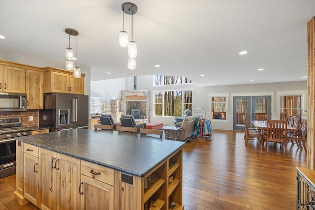 701 Chalupsky Ave SE, New Prague, MN 56071 - kitchen featuring stainless steel appliances, dark countertops, dark wood-style flooring, backsplash, and a kitchen island