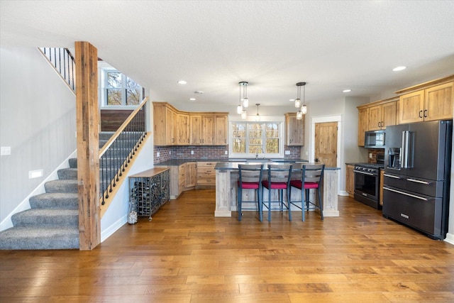 701 Chalupsky Ave SE, New Prague, MN 56071 - kitchen with high end fridge, stainless steel microwave, gas range oven, a kitchen island, and light wood finished floors