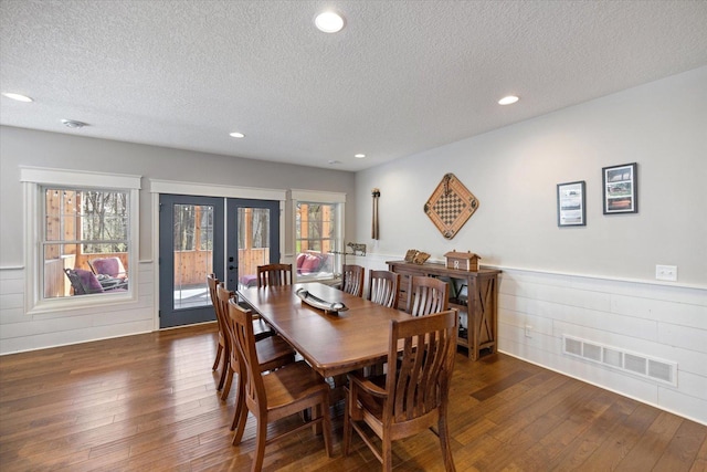 701 Chalupsky Ave SE, New Prague, MN 56071 - dining area with dark wood-type flooring, a textured ceiling, french doors, a wainscoted wall, and plenty of natural light