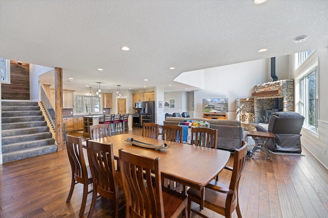 701 Chalupsky Ave SE, New Prague, MN 56071 - dining space featuring hardwood / wood-style floors, stairs, recessed lighting, a textured ceiling, and a fireplace