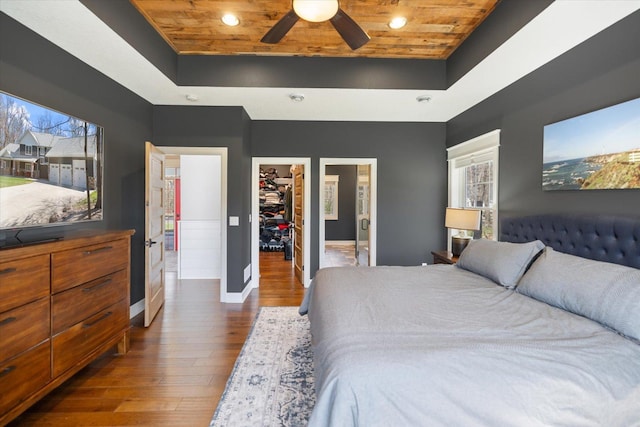 701 Chalupsky Ave SE, New Prague, MN 56071 - bedroom featuring wooden ceiling, a tray ceiling, a walk in closet, baseboards, and wood finished floors
