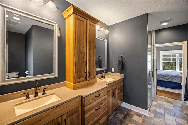 701 Chalupsky Ave SE, New Prague, MN 56071 - bathroom featuring double vanity, ensuite bathroom, baseboards, a textured ceiling, and a stall shower