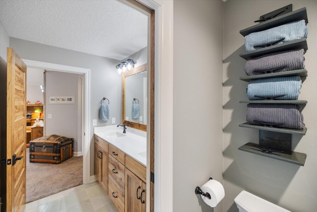 701 Chalupsky Ave SE, New Prague, MN 56071 - bathroom with double vanity, toilet, a textured ceiling, and baseboards