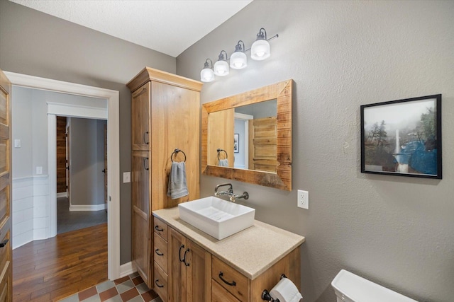 701 Chalupsky Ave SE, New Prague, MN 56071 - bathroom featuring vanity, toilet, wood finished floors, and baseboards