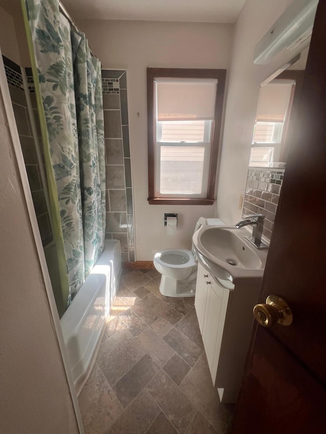 1008 4th St E, Saint Paul, MN 55106 - bathroom with shower / bath combo, toilet, vanity, stone finish floors, and baseboards