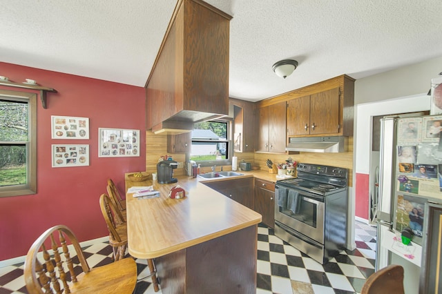 1418 345th Ave, Frederic, WI 54837 - kitchen with stainless steel appliances, tile patterned floors, under cabinet range hood, healthy amount of natural light, and a textured ceiling