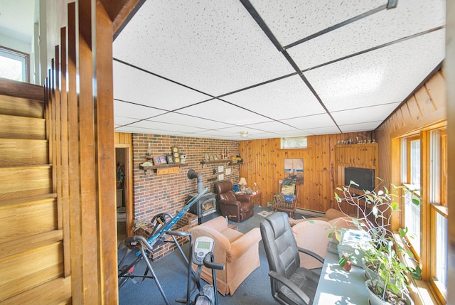 1418 345th Ave, Frederic, WI 54837 - living room featuring wooden walls, a paneled ceiling, a wood stove, and stairway