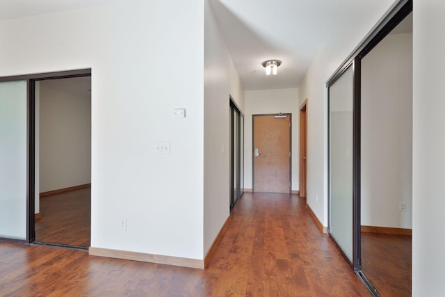corridor with wood finished floors and baseboards