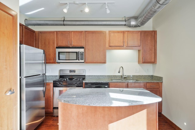 kitchen featuring stainless steel appliances, a sink, dark wood-style flooring, and light stone countertops