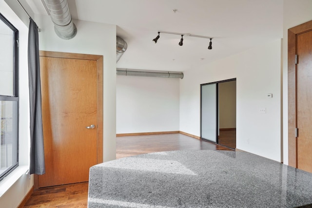 unfurnished room featuring track lighting and wood finished floors