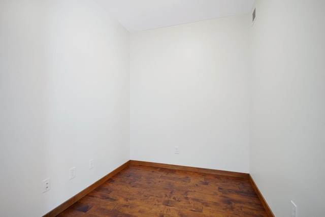 unfurnished room featuring baseboards and dark wood-type flooring