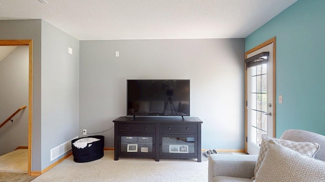 living area with carpet floors, baseboards, an upstairs landing, and a textured ceiling