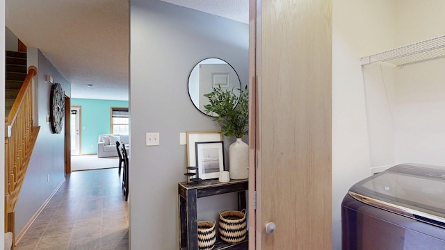 corridor featuring washer / clothes dryer, baseboards, and a textured ceiling