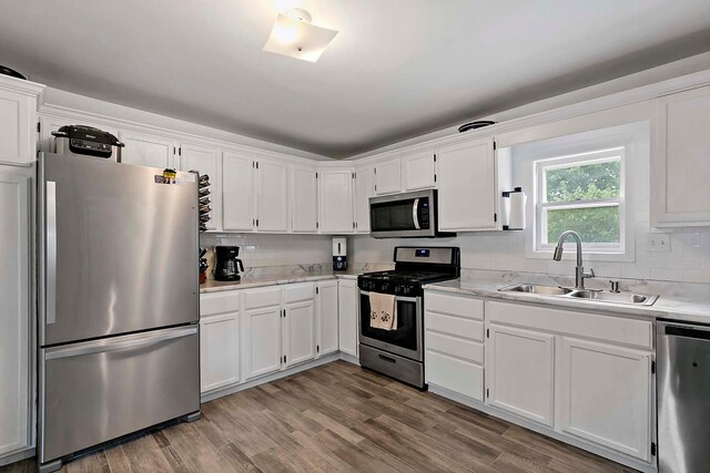 706 Broad St, Mankato, MN 56001 - kitchen featuring appliances with stainless steel finishes, a sink, white cabinetry, tasteful backsplash, and wood finished floors