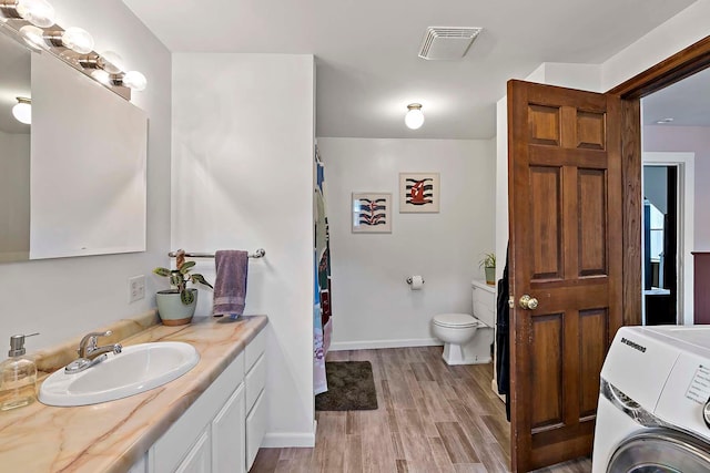706 Broad St, Mankato, MN 56001 - full bath with washer / clothes dryer, vanity, wood finished floors, toilet, and baseboards