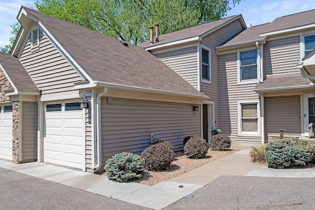 view of side of home with an attached garage and a shingled roof