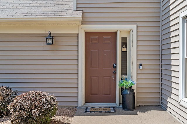 view of exterior entry with a shingled roof