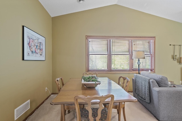 dining area featuring light colored carpet and vaulted ceiling