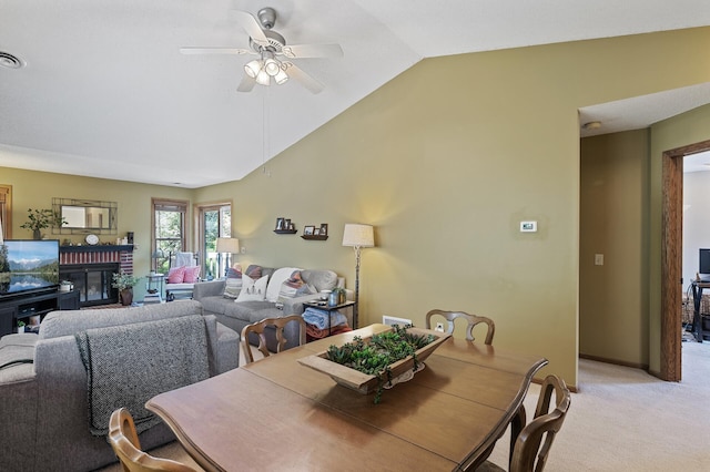 dining space featuring lofted ceiling, a ceiling fan, light carpet, and a fireplace