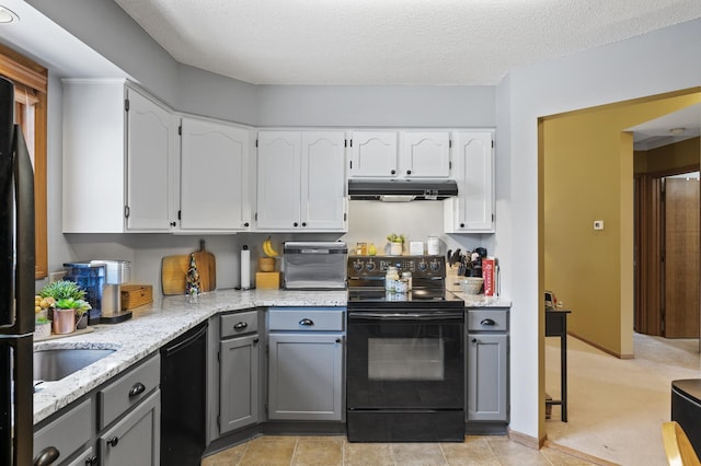 kitchen with black appliances, gray cabinetry, under cabinet range hood, light stone counters, and white cabinets