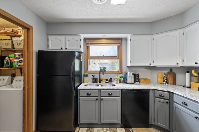 kitchen with black appliances, a sink, gray cabinetry, washing machine and dryer, and white cabinets