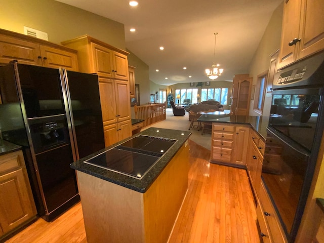 kitchen with black appliances, open floor plan, lofted ceiling, a center island, and light wood-style flooring