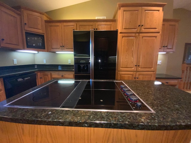 kitchen featuring black appliances, lofted ceiling, dark stone countertops, and a center island