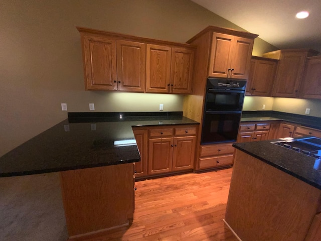 kitchen with light wood-style flooring, lofted ceiling, a peninsula, dark stone countertops, and recessed lighting