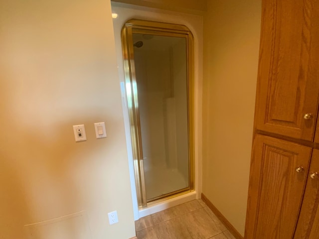 corridor featuring light tile patterned flooring and baseboards