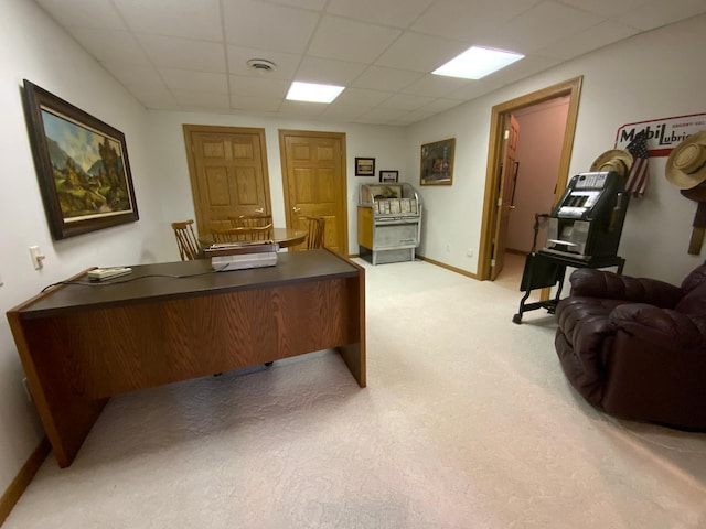 office space with a paneled ceiling, light carpet, and baseboards