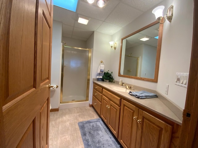 full bath with a paneled ceiling, a shower stall, vanity, and tile patterned floors