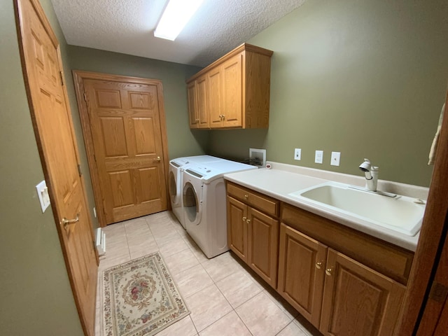 clothes washing area with cabinet space, a textured ceiling, light tile patterned floors, and washing machine and clothes dryer