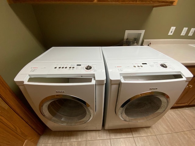 clothes washing area with separate washer and dryer and light tile patterned flooring