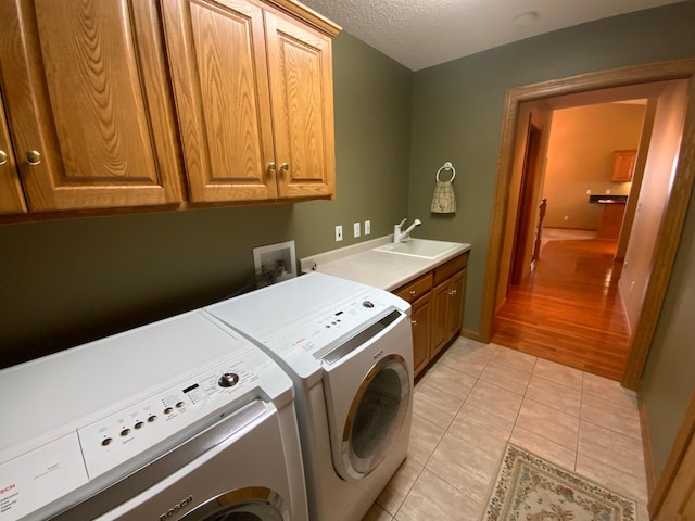 washroom with washer and dryer, cabinet space, light tile patterned flooring, and a textured ceiling