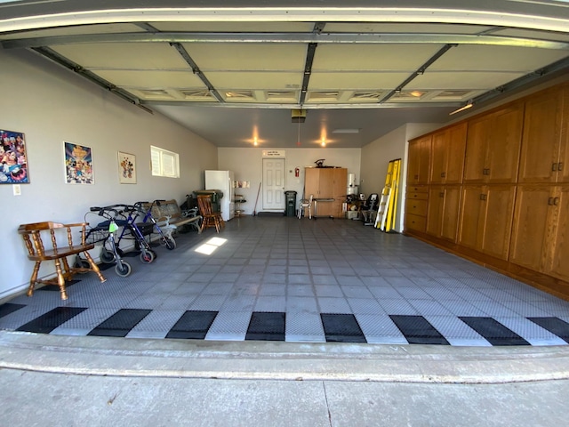 garage featuring a garage door opener and freestanding refrigerator