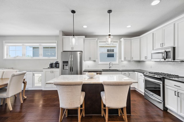8172 Virginia Ln, Savage, MN 55378 - kitchen with appliances with stainless steel finishes, a sink, a kitchen island, dark wood-style floors, and tasteful backsplash
