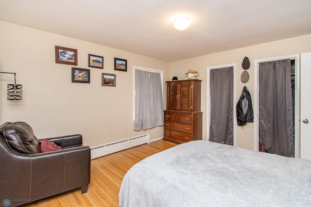 bedroom with a baseboard heating unit and light wood-type flooring