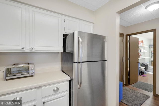 3300 Louisiana Ave S Unit 517, Saint Louis Park, MN 55426 - kitchen featuring freestanding refrigerator, white cabinetry, light countertops, a textured ceiling, and wood finished floors