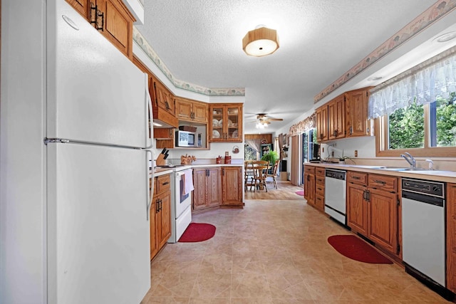 kitchen featuring white appliances, brown cabinets, light countertops, a textured ceiling, and a ceiling fan