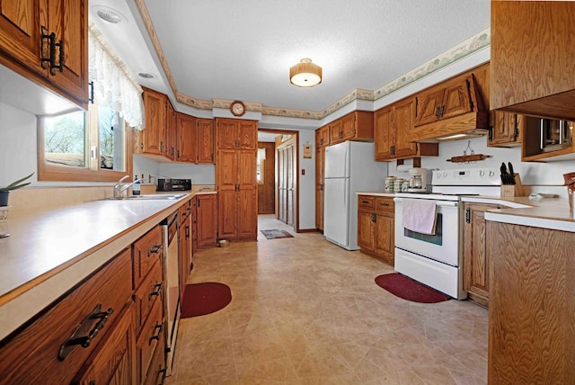 kitchen featuring white appliances, a sink, brown cabinets, light countertops, and a textured ceiling