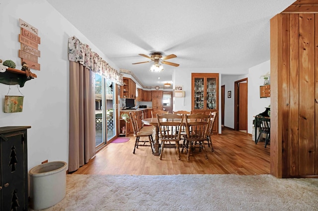 dining area with ceiling fan, light wood-style flooring, and a textured ceiling
