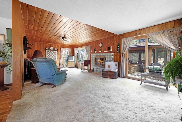 carpeted living area with wood walls and a fireplace