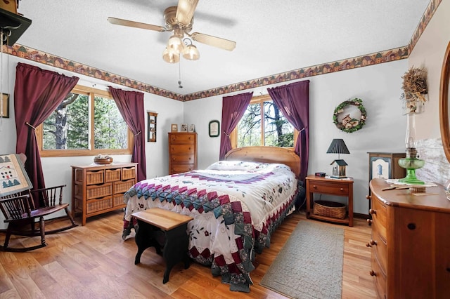 bedroom featuring light wood finished floors, a textured ceiling, and a ceiling fan