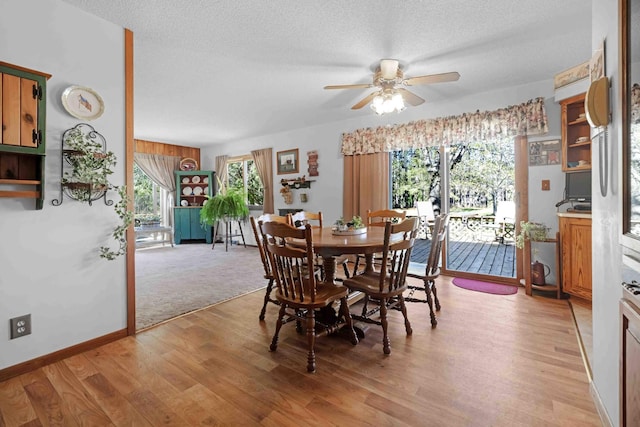 dining space with ceiling fan, light wood finished floors, a textured ceiling, and baseboards
