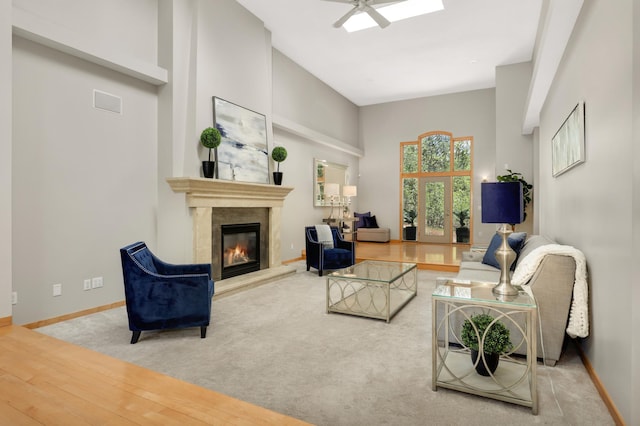 carpeted living room featuring a high end fireplace, baseboards, and ceiling fan