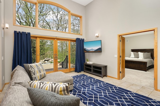 living room featuring french doors, a high ceiling, tile patterned floors, baseboards, and carpet