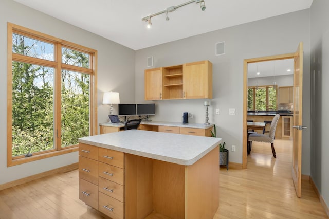 kitchen with light brown cabinets, light countertops, light wood-style flooring, and baseboards