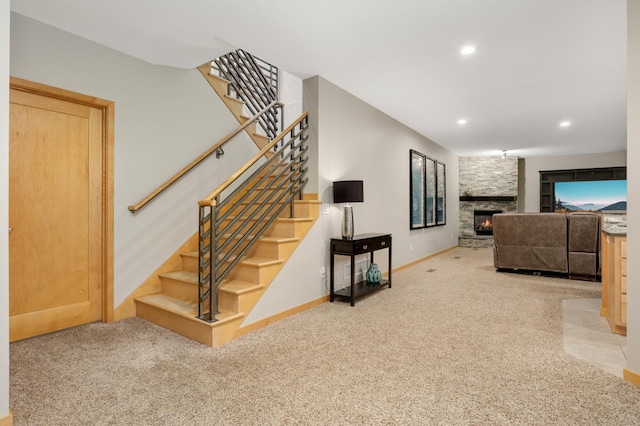 staircase with carpet, a stone fireplace, recessed lighting, and baseboards