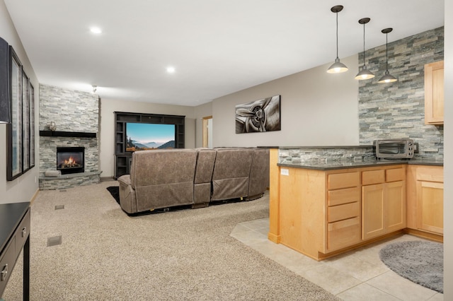 kitchen featuring light brown cabinets, a fireplace, dark countertops, open floor plan, and tasteful backsplash